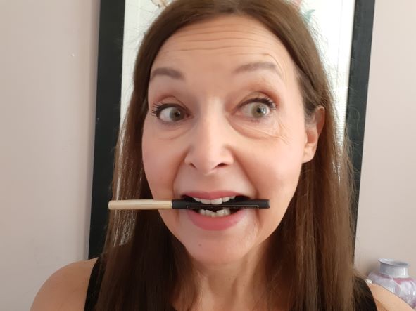 woman with makeup brush between her teeth
